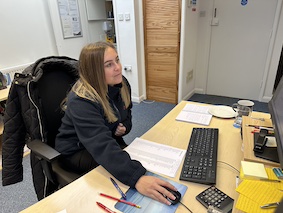 Justine, admin assistant sat at computer