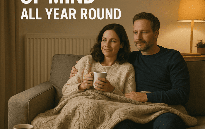 two people sat on sofa with cup of tea looking happy