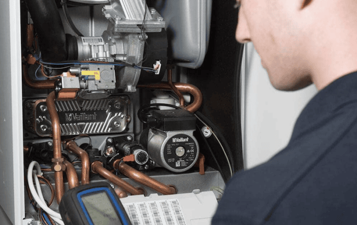 Boiler installation in Chichester. Image shows an engineer installing and checking a boiler.