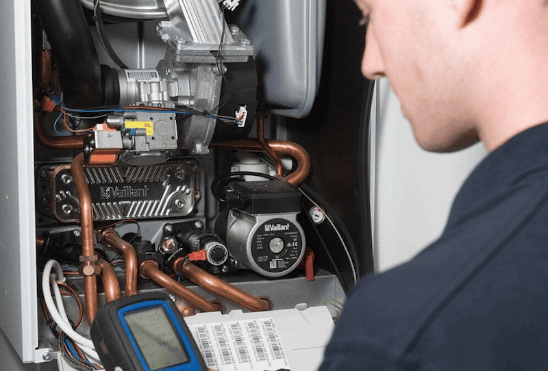 Boiler installation in Chichester. Image shows an engineer installing and checking a boiler.